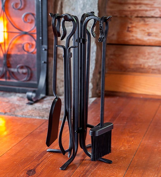 A fireplace tool set beside a blazing fireplace