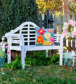 OUTDOOR BENCHES & CHAIRS > Image of a white wood bench with  floral pillow on it and metal statuary in backyard setting.