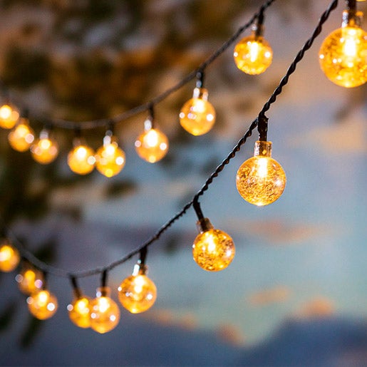 Multi-function solar ball string lights with 50 warm white LEDs lit up at dusk