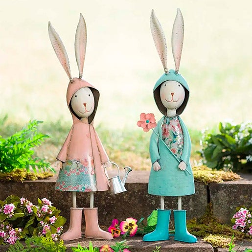 2 cute metal bunny statuary dressed in raincoats and boots holding watering can and flower