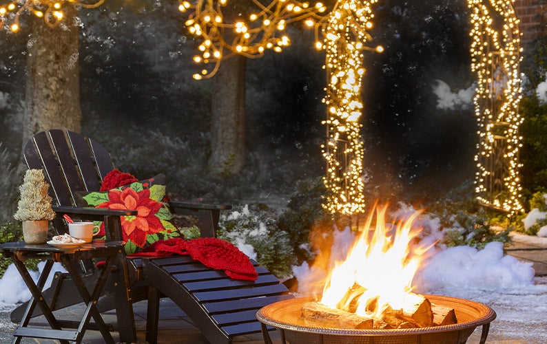 Image of backyard firepit at night with string lights on trees