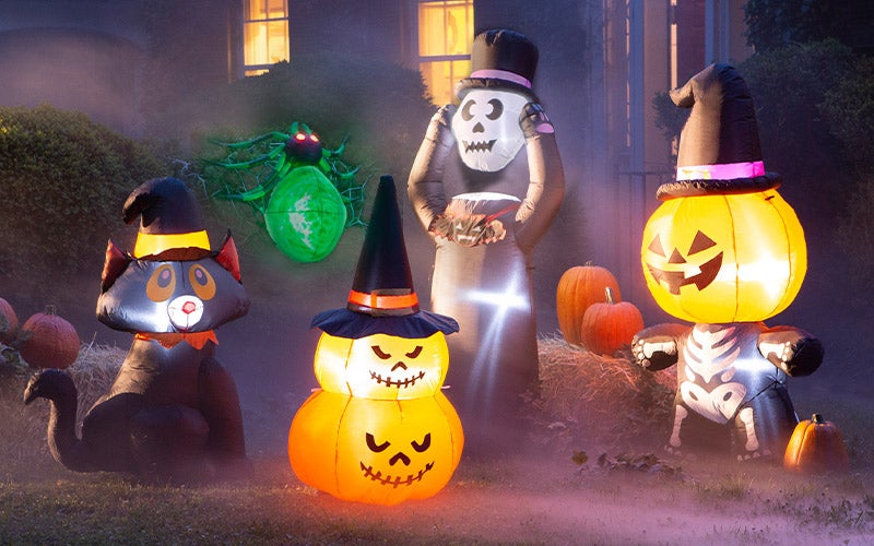 Five lighted inflatable halloween yard decorations glow in a front yard