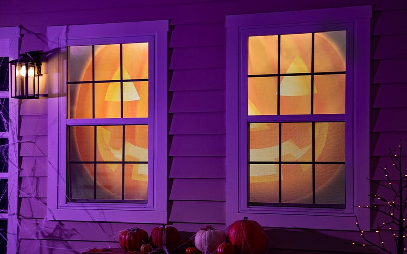 Window shades with the image of a giant jack-o-lantern hang in the windows of a house