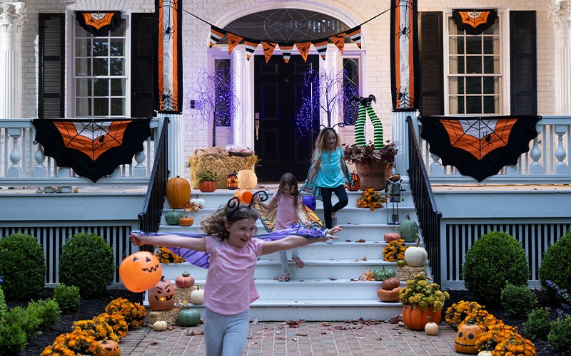 Trick-or-treaters run off a porch decorated with halloween spider bunting