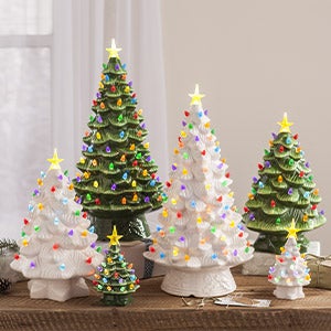 A collection of vintage lighted ceramic Christmas trees on a tabletop