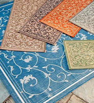 Veranda scroll indoor/outdoor rugs in varying colors layered on top of each other