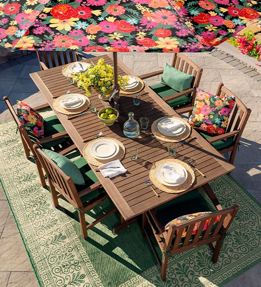 SHOP OUTDOOR DINING FURNITURE. Image of Lancaster collection eucalyptus wood etension table and 6 chairs with cushions and colorful umbrella on a back patio.