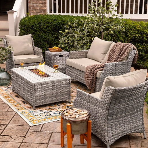 St. Helena Wicker Patio and Fire Pit Seating Set, 5 piece on a patio with planter, outdoor rug  and pillows