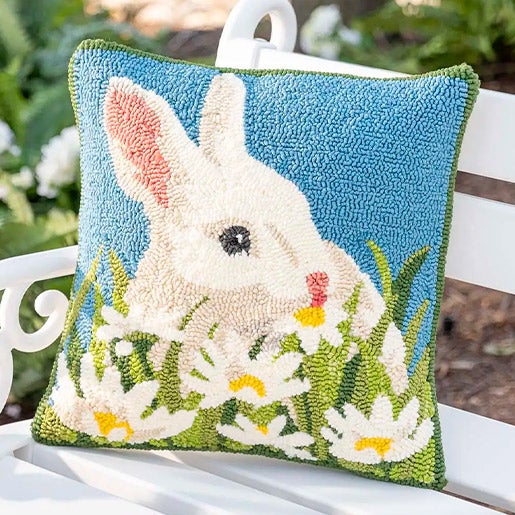 bunny themed hooked pillow on a white bench