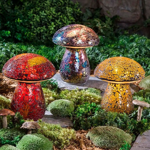 Three colorful mosaic glass mushrooms lit up at night