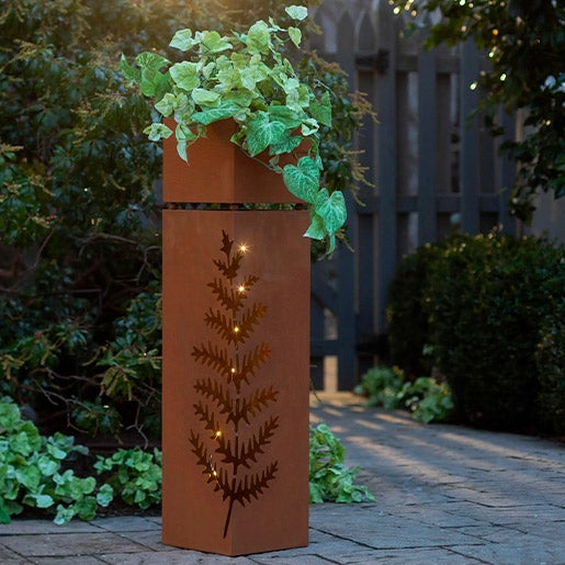 Rectangular metal planter with cutout design of fern on the side and lighting inside