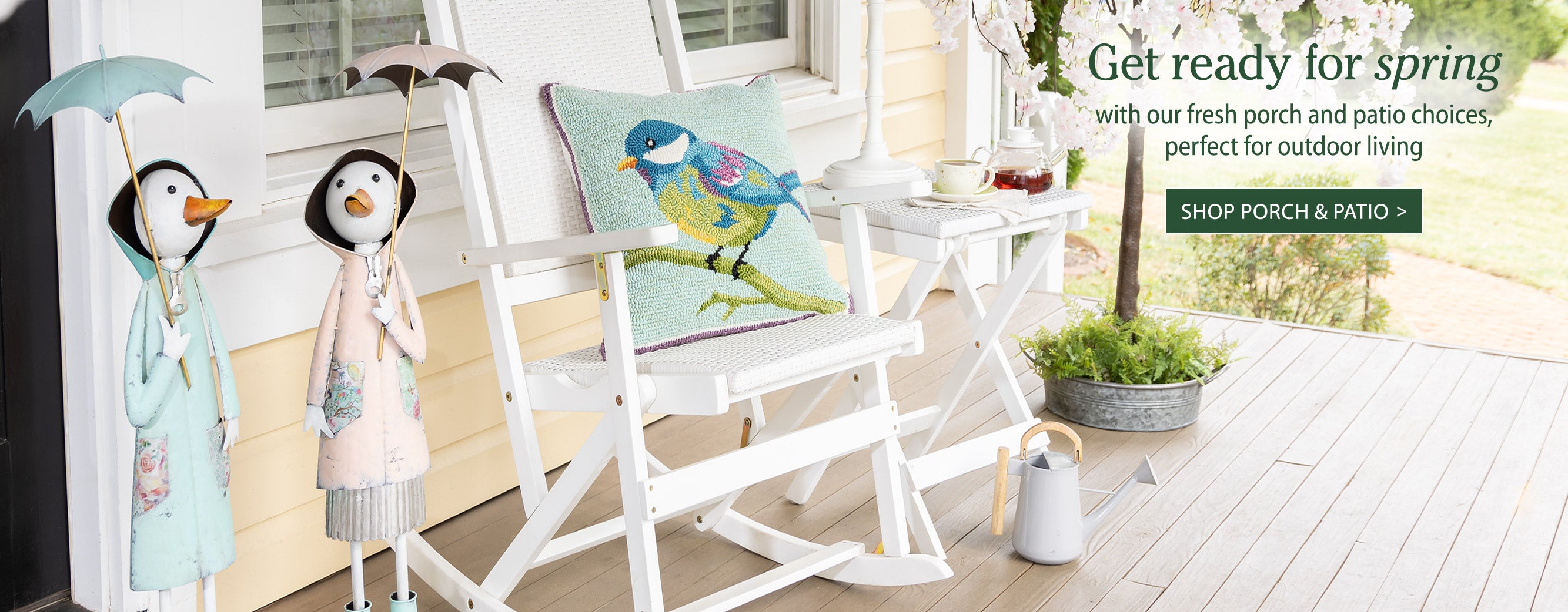 Image of front porch with white rocker, statues with umbrellas & cherry trees. Get ready for spring with our fresh portch and patio choices, perfect for outdoor living SHOP PORCH & PATIO