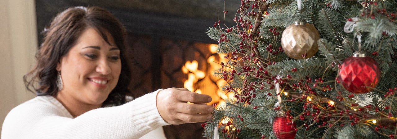 woman hanging ornaments on tree