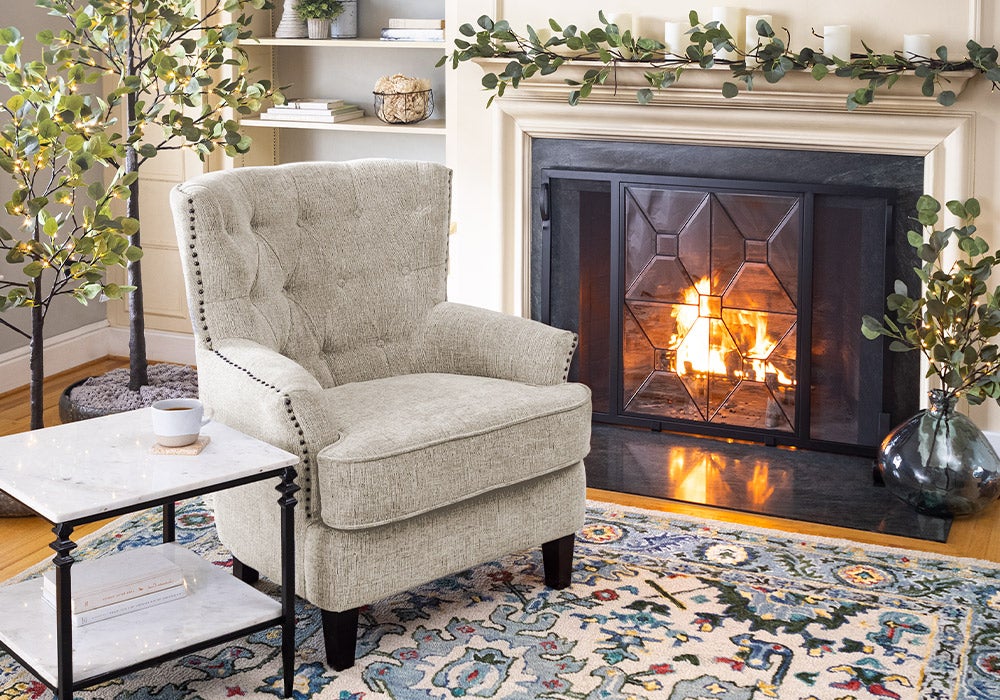 white chair in front of fireplace with greenery on mantel