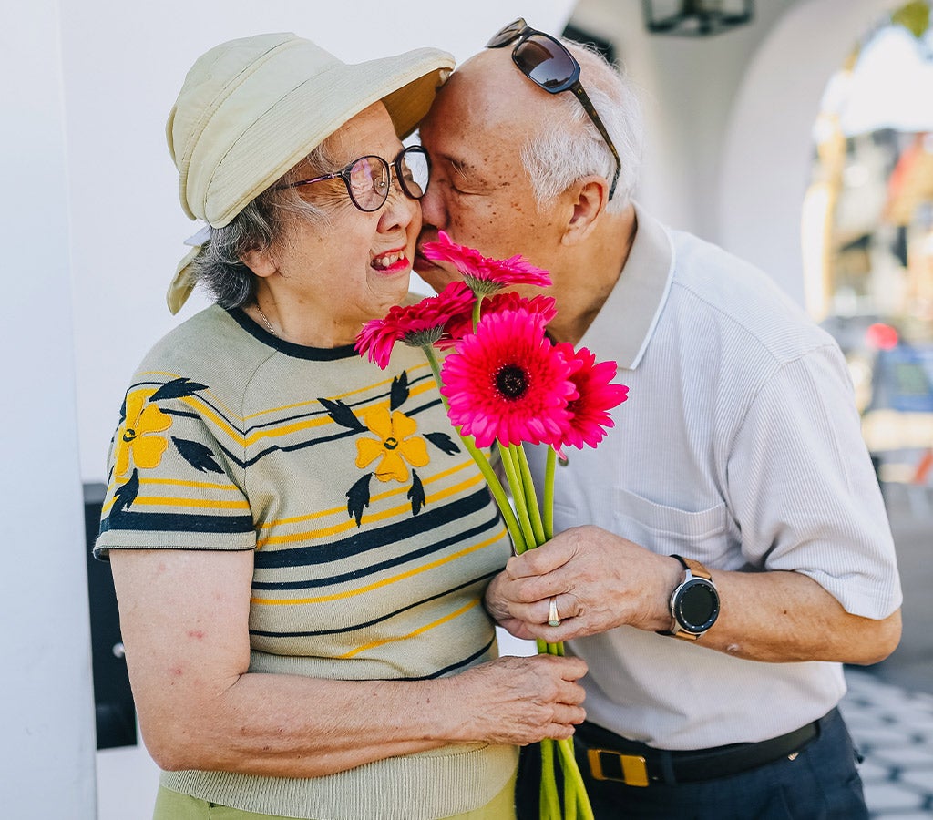 elderly couple smiling with flowers