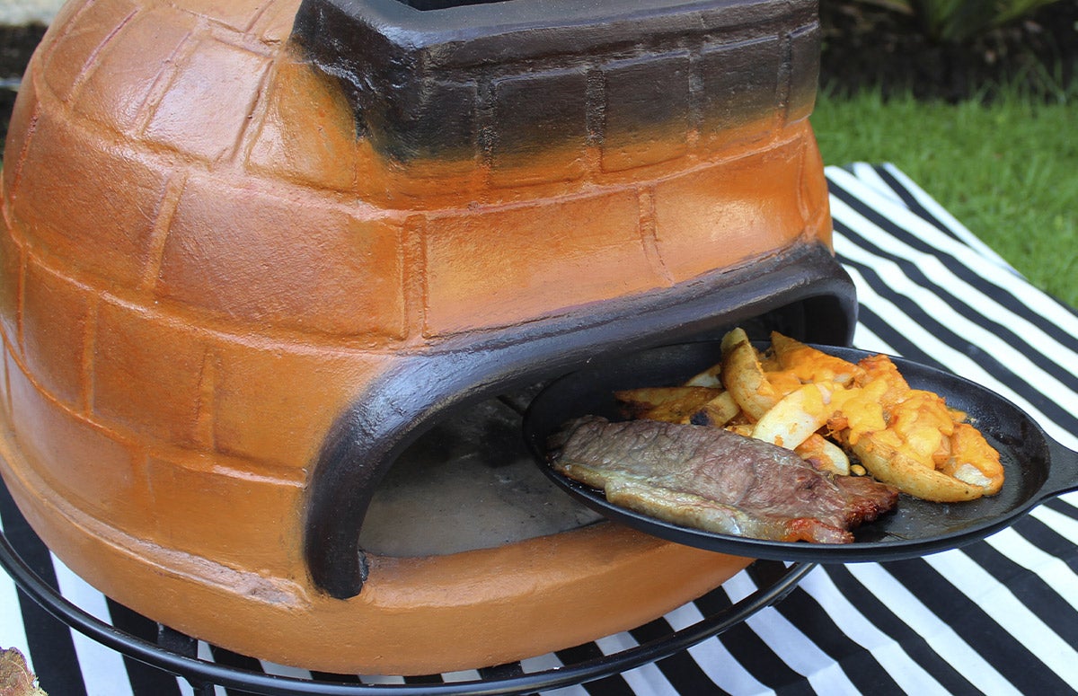 person putting steak and fries in pizza oven