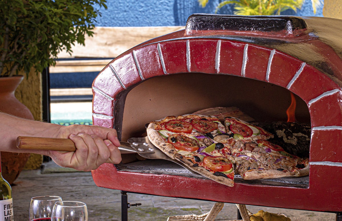 person putting pizza in pizza oven