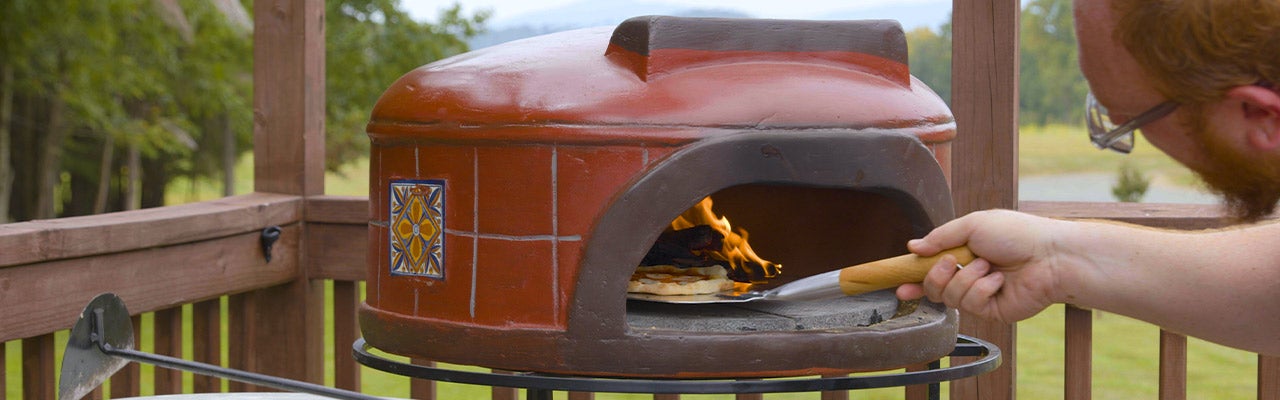 person putting pizza in pizza oven