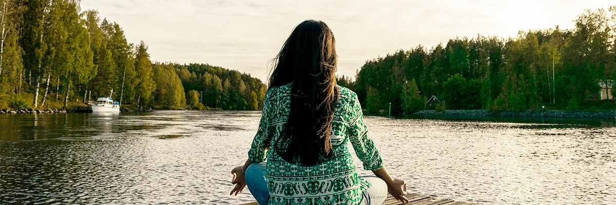 woman meditating on dock on water