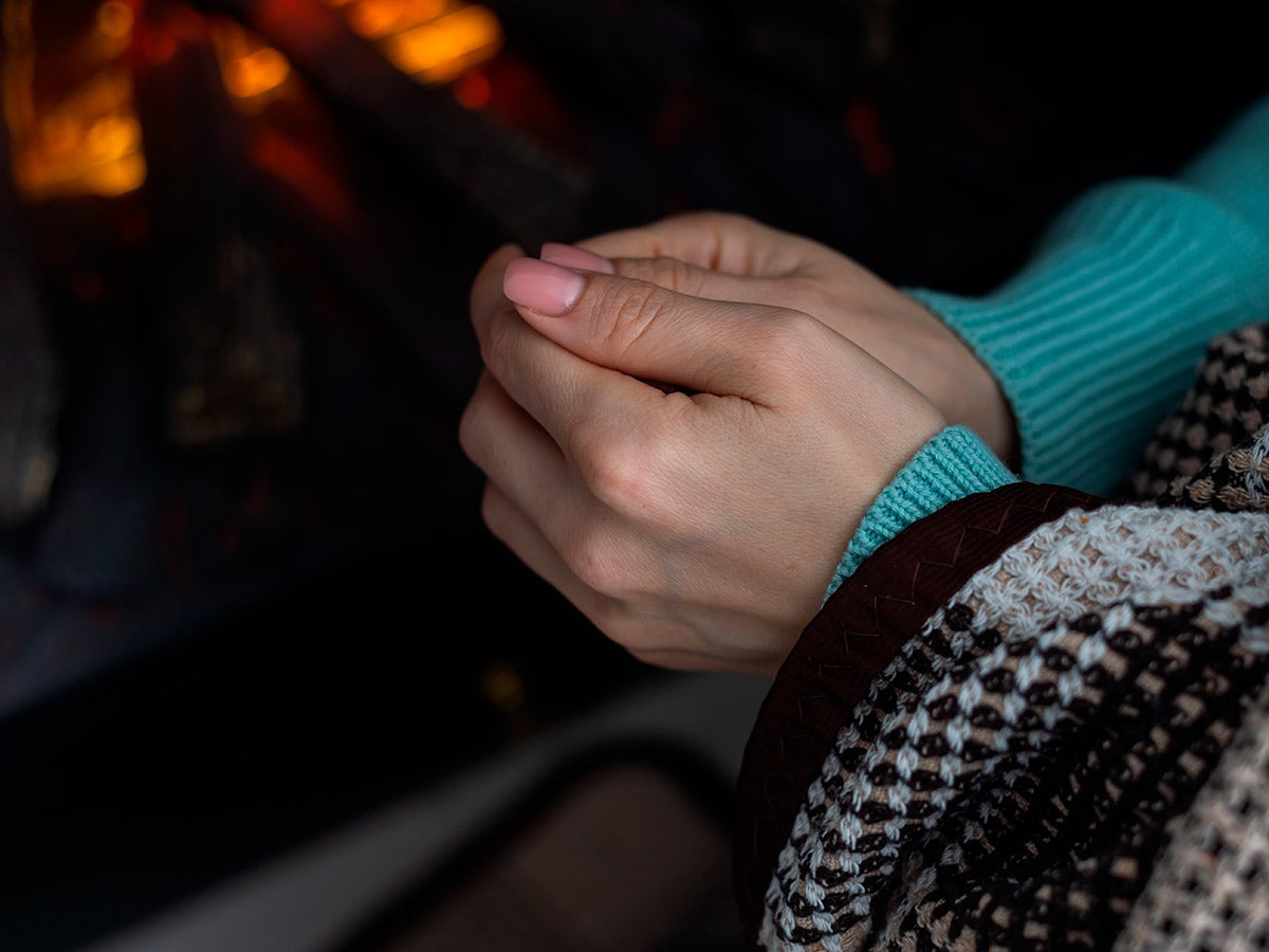 woman warming hands to heater