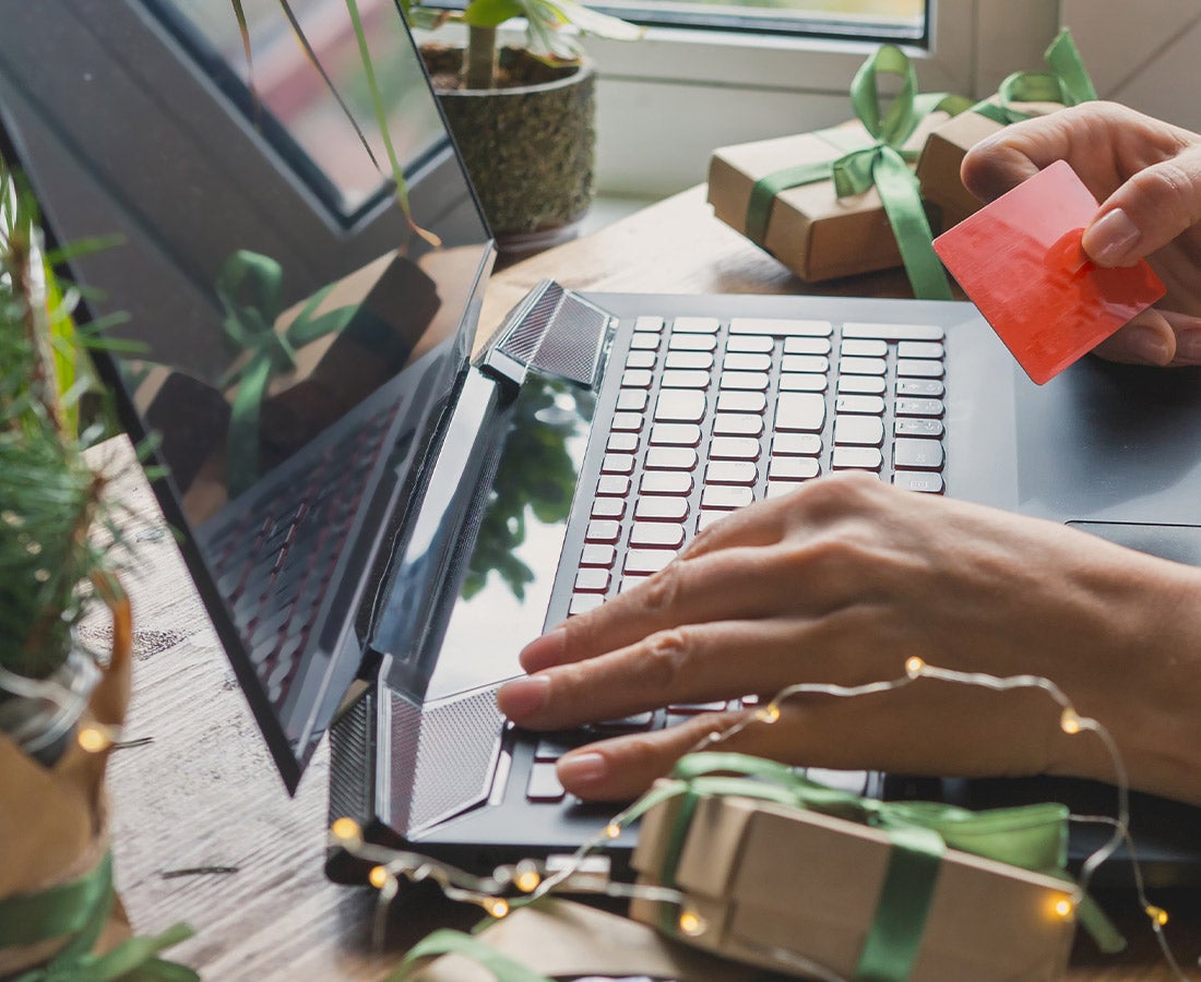 person shopping on computer with wrapped gifts