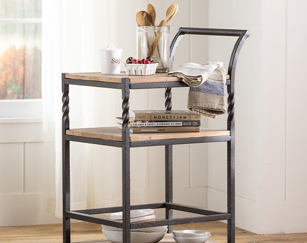 A Deep Creek rolling bar cart with a distressed wood top and metal frame with twisted accents.